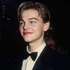 a young man in a tuxedo smiles at the camera while wearing a black bow tie