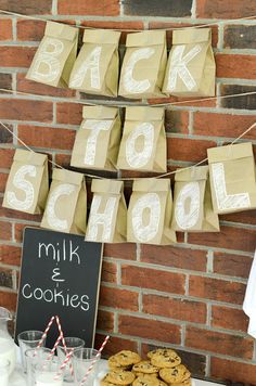 cookies and milk are on display in front of a brick wall with paper bags that say back to school