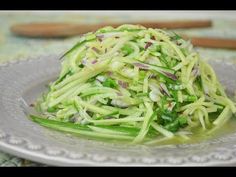 a white plate topped with cucumber salad on top of a table