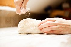 a person kneading dough on top of a table