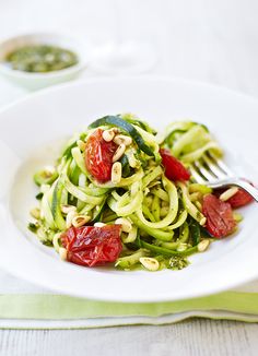 a white plate topped with zucchini noodles and tomatoes