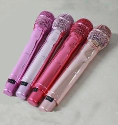 four different colored microphones are lined up in a row on a white table top