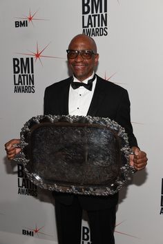 a man in a tuxedo is holding up a silver platter that says bmi latin awards