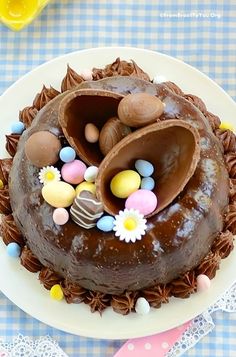 a chocolate easter cake on a plate with candy eggs and flowers in the shape of an egg