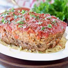 the meatloaf is covered with sauce and parmesan cheese on top of noodles