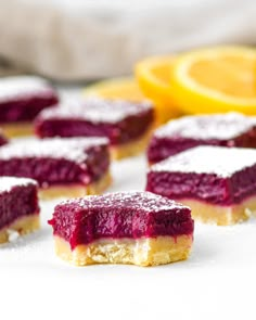 several pieces of cake sitting on top of a white table next to sliced lemons