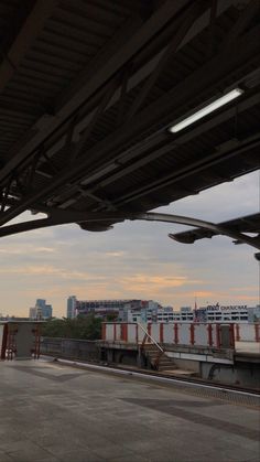 an empty train station with trains on the tracks and buildings in the backgroud