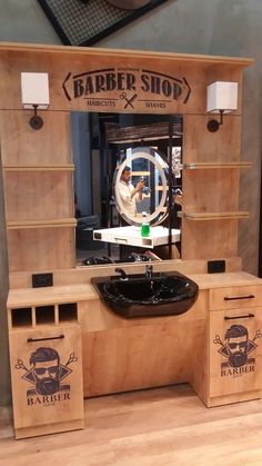 a barber shop with wooden shelves and black sink in front of the mirror on the wall