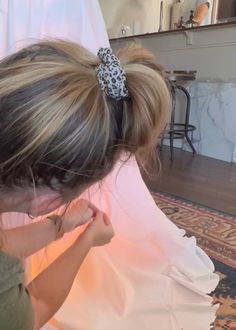 a woman sitting on the floor with her hair tied in a pony tail and wearing a leopard print bow