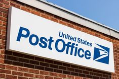 a sign on the side of a brick building that says post office with an envelope