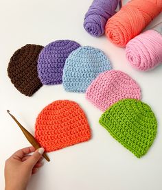 the crocheted hats are being worked on by someone who is holding a pair of scissors