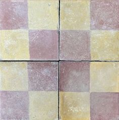 four square tiles with different colors and patterns on the floor, one is pink, yellow and white