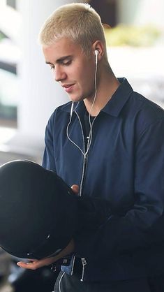 a young man wearing headphones is looking at his hat