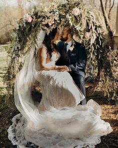 a bride and groom sitting under an arch with flowers