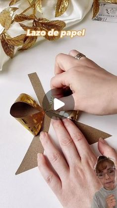 a person cutting paper with scissors on top of a white table next to gold foil