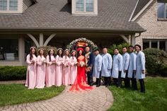 a group of people standing in front of a house posing for a photo with the bride and groom