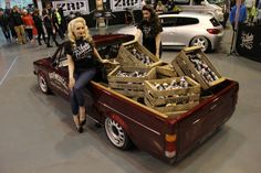 two women sitting on the back of a truck with crates in it's bed