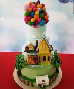 a birthday cake with balloons on top of it and a house in the middle that says happy birthday