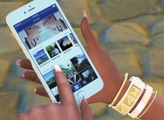 a woman holding an iphone with the app on her wrist and bracelet around her arm