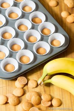 a muffin tin filled with peanut butter next to a banana on a wooden table