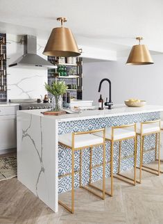 an instagram page with two gold lamps and three white stools in the kitchen