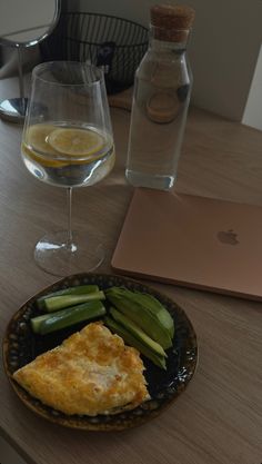 there is a plate of food on the table with a glass of wine next to it