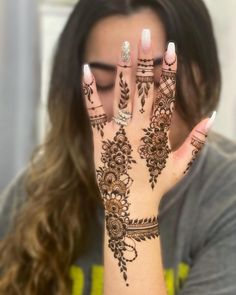 a woman holding her hands up with henna on it