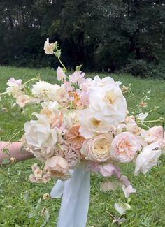 a bridal bouquet with pink and white flowers in the middle of a grassy field