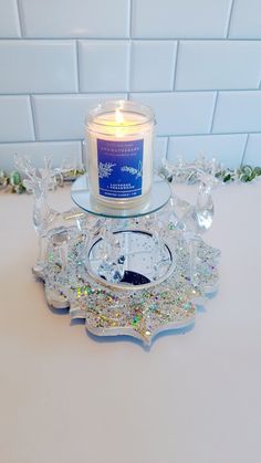 a candle sitting on top of a glass plate next to a clock and snowflakes