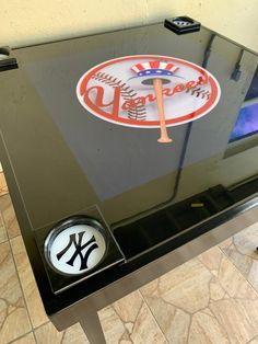 the new york yankees logo is on top of a glass table with a baseball bat