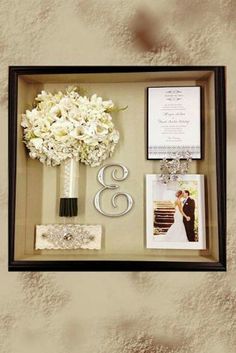 a wedding gift with flowers and photos in a shadow box on the wall next to it