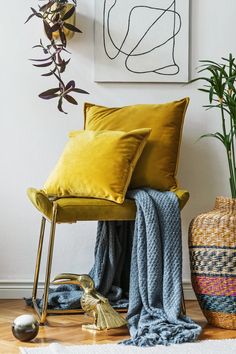 a yellow chair sitting next to a potted plant