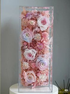 a clear box filled with lots of pink and white flowers on top of a table