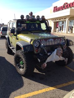 a group of people riding on the back of a green jeep in a parking lot