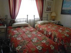 two beds in a hotel room with red and white comforters on top of them