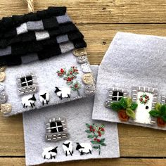 three small houses made out of felt with sheep and flowers on the front, one in black and white