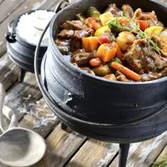 a pot filled with stew sitting on top of a wooden table