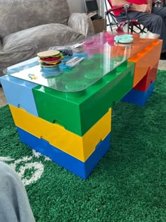 a coffee table made out of legos on green carpeted area with couch in background