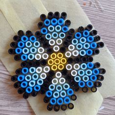 an ornament made out of black, white and blue beads on top of a piece of paper