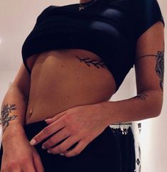 a woman with tattoos on her stomach wearing a black skirt and holding a handbag