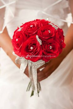 the bride's bouquet is made up of red roses and diamond brooches