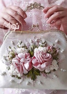 a close up of a person holding a purse with pink flowers on the front and side