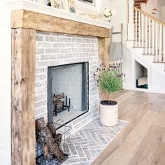 a white brick fireplace with potted plants on the mantle and stairs in the background