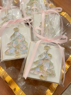 four small christmas cards in plastic bags on a table with pink ribbons and bows around them