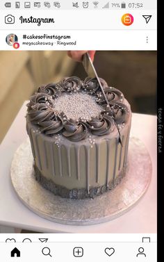 someone cutting into a chocolate cake on top of a white table with an instagram sign above it