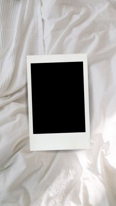 an empty square photo frame sitting on top of a white sheet