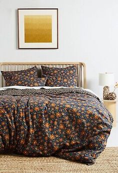 a bedroom with a bed covered in a blue and orange flowered comforter set