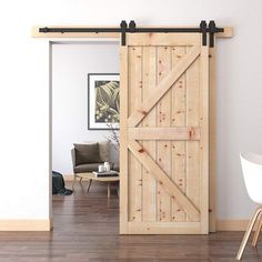 an open sliding barn door in a living room with hardwood floors and white chairs around it