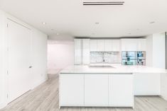 an empty kitchen with white cabinets and marble counter tops