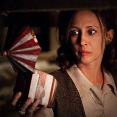 a woman holding a red and white fan in her hand